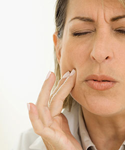 Woman with tooth pain places her fingers on her cheek